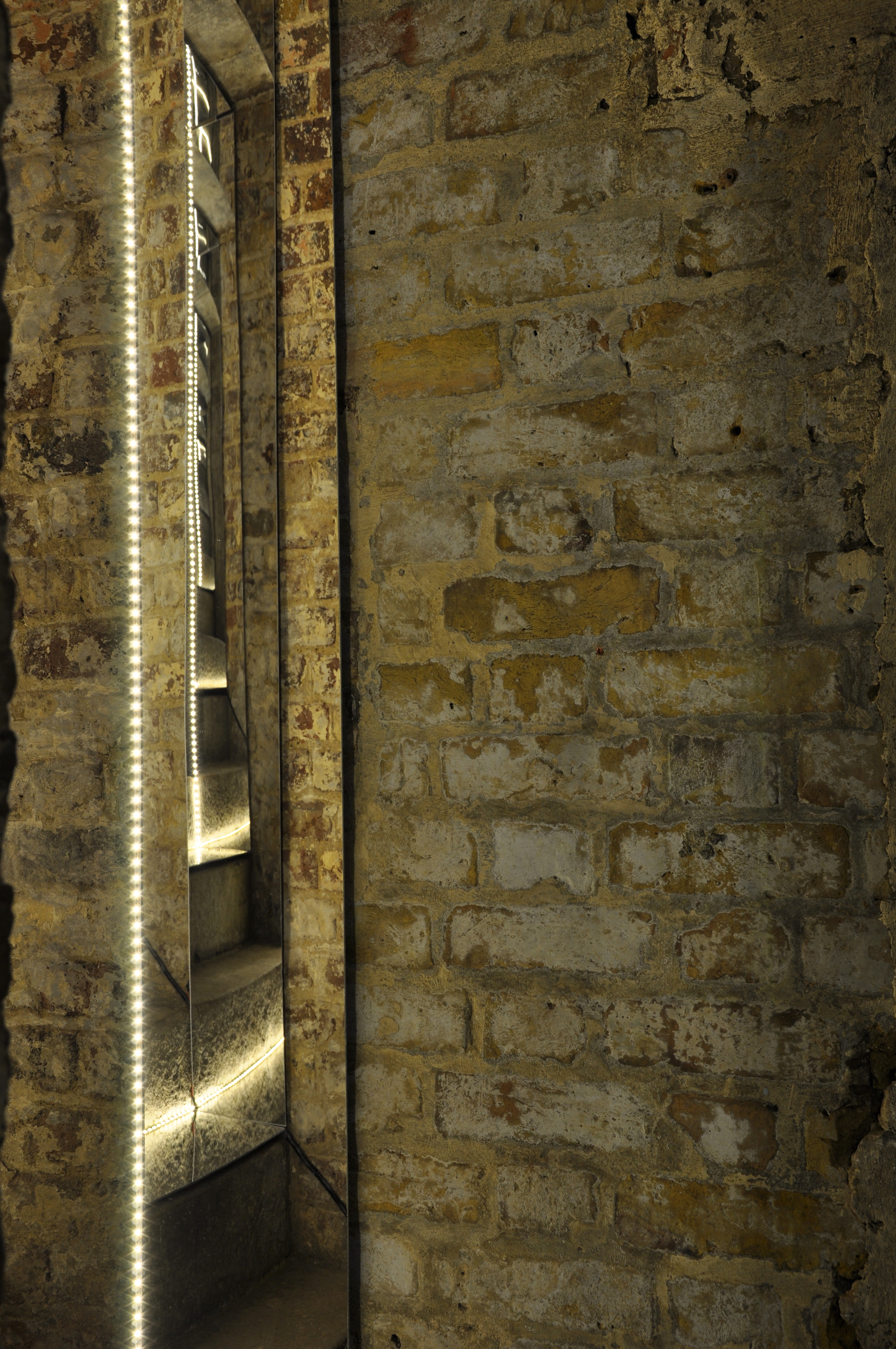 Introspection — mirrored stairwell against exposed brick
