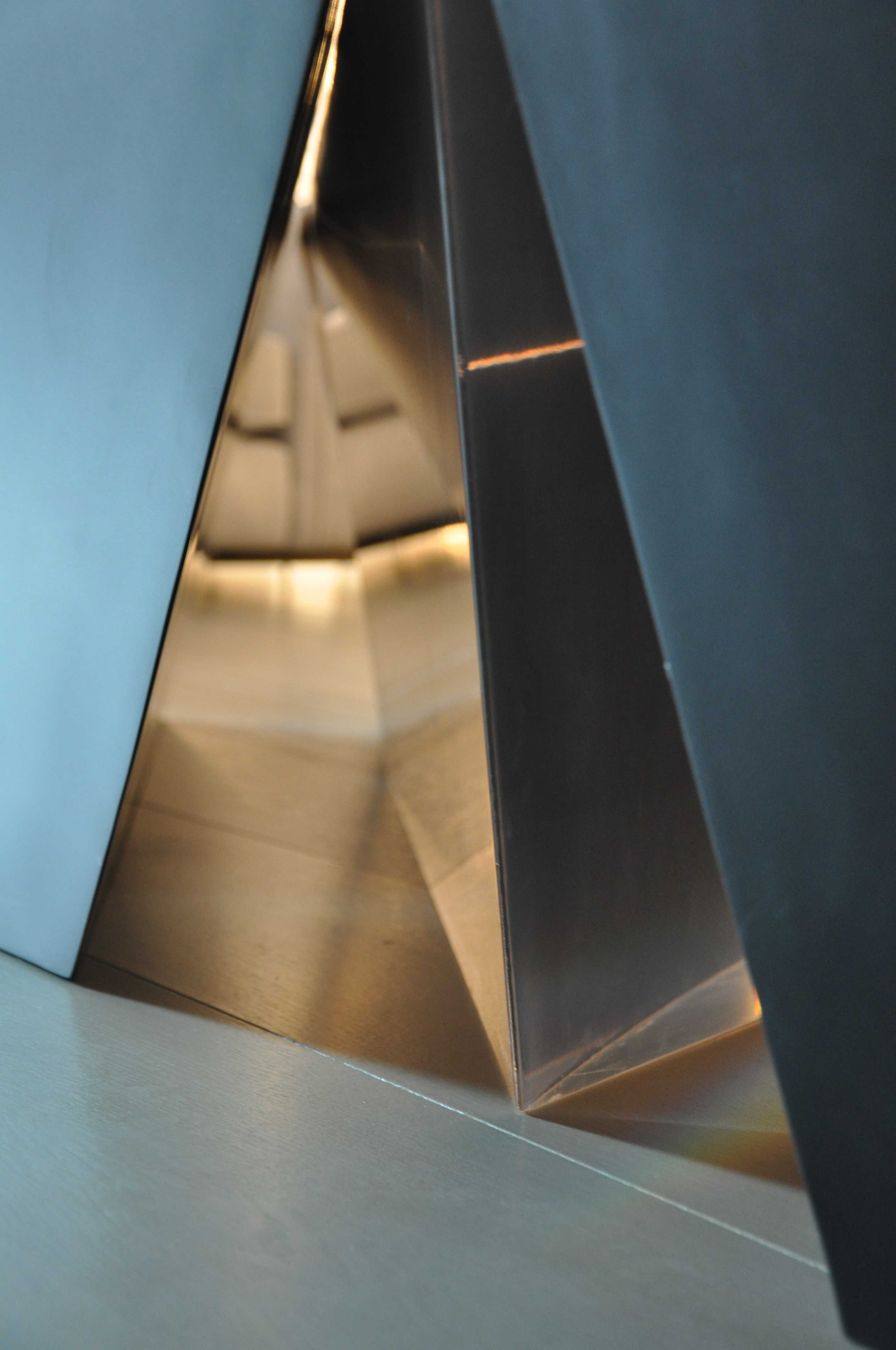Interior detail — polished bronze reflecting a corridor into a sculptural void